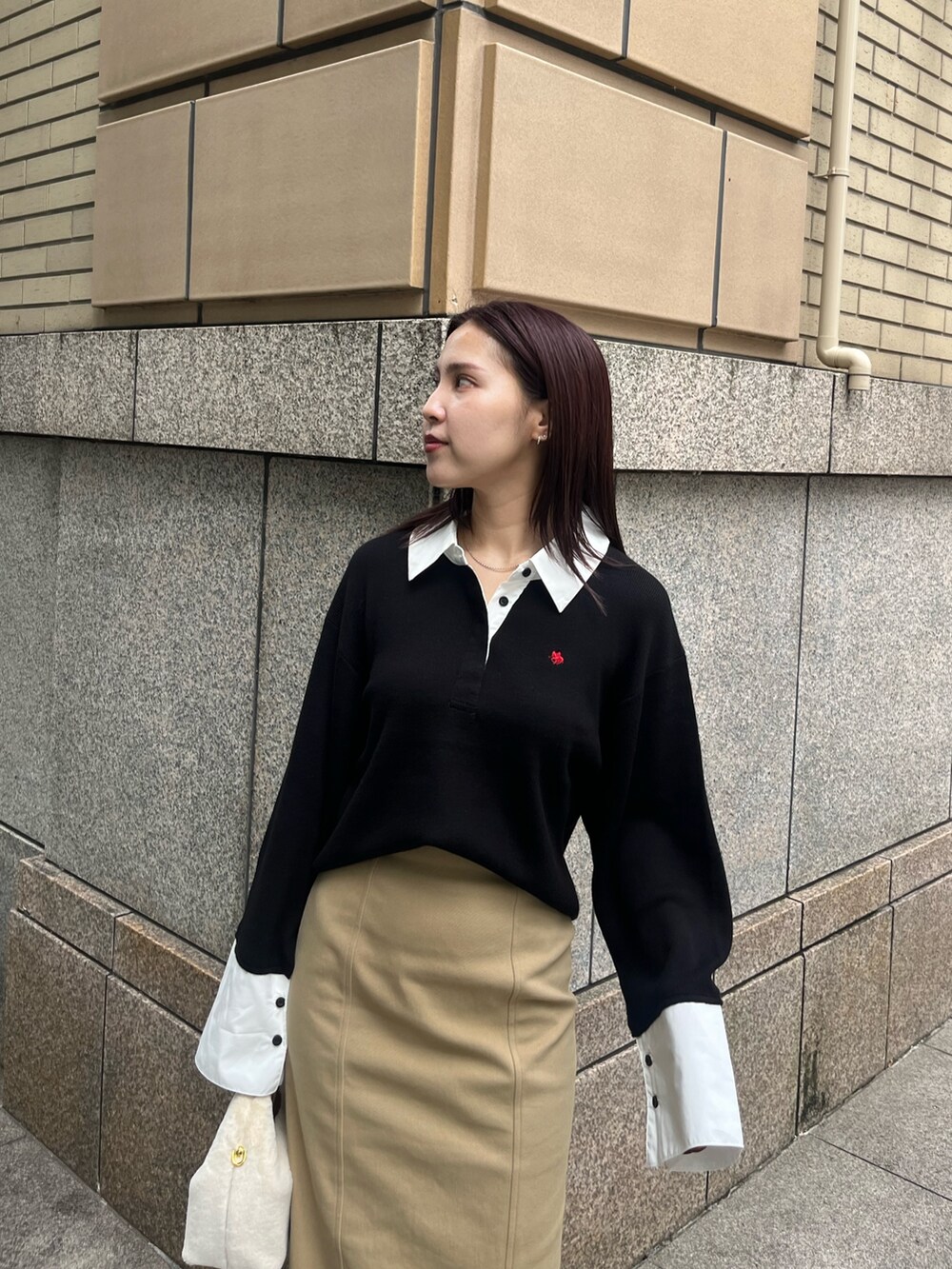 ベージュ系のスカート、ホワイト系のハンドバッグ、ブラック系のブーツを着用したレディースの秋コーディネートの4枚目の写真