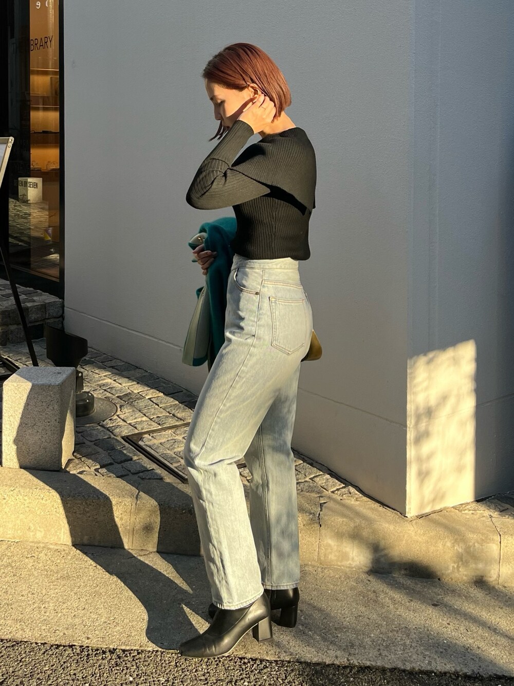 ブルー系のデニムパンツ、ブルー系のカーディガン/ボレロ、ブラック系のニット/セーターを着用したレディースの冬コーディネートの4枚目の写真