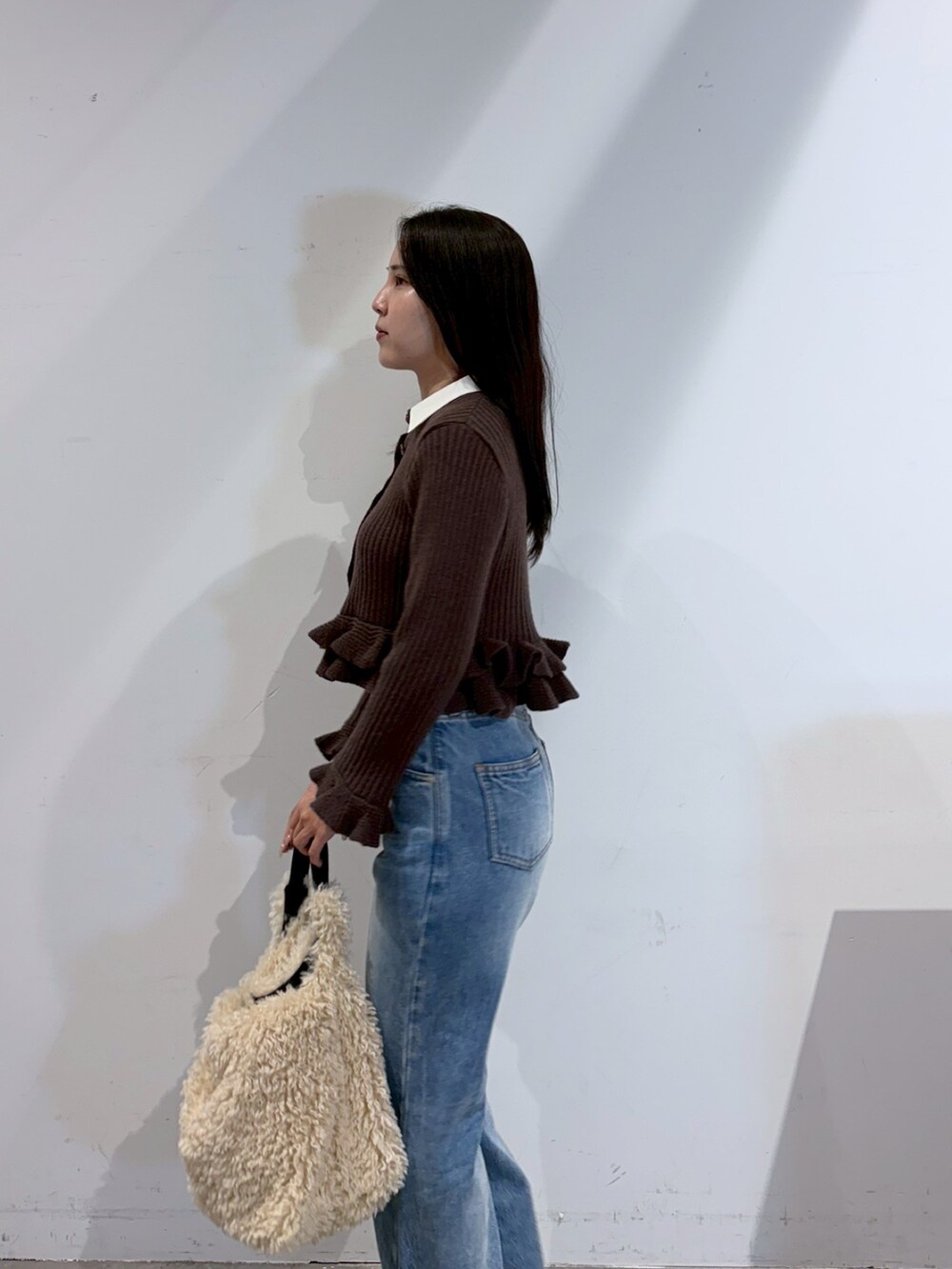ブラウン系のニット/セーター、ブルー系のデニムパンツ、ブラック系のブーツを着用したレディースの夏コーディネートの5枚目の写真