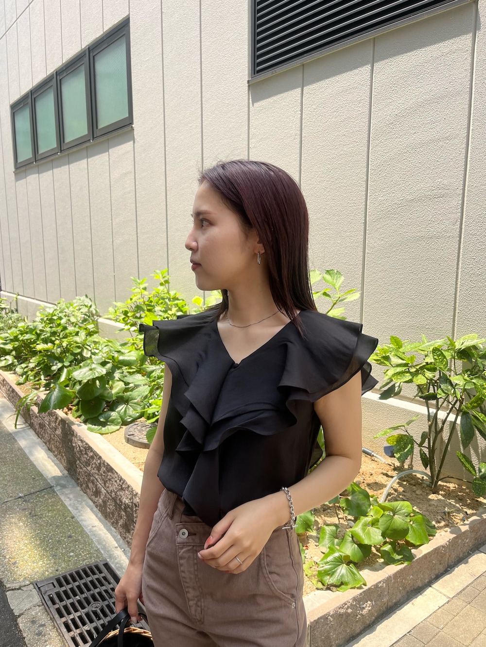 ベージュ系のデニムパンツ、ブラウン系のハンドバッグ、ブラック系のシャツ/ブラウスを着用したレディースの夏コーディネートの6枚目の写真