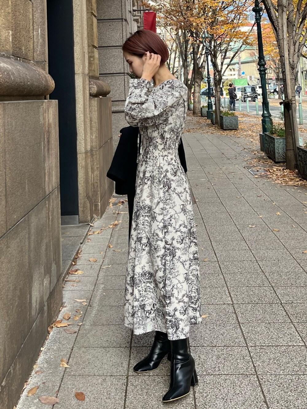 ホワイト系のワンピース、ブラック系のハンドバッグ、ブラック系のブーツを着用したレディースの冬コーディネートの3枚目の写真