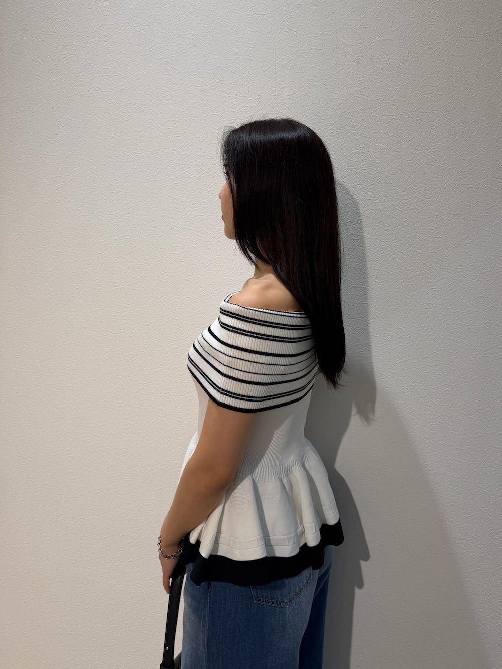 ブルー系のデニムパンツ、ブラック系のハンドバッグ、グリーン系のパンプスを着用したレディースの夏コーディネートの5枚目の写真