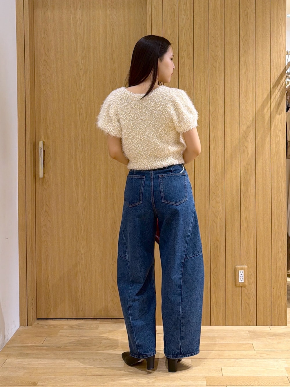 ブルー系のデニムパンツ、レッド系のハンドバッグ、ブラック系のブーツを着用したレディースの秋コーディネートの6枚目の写真