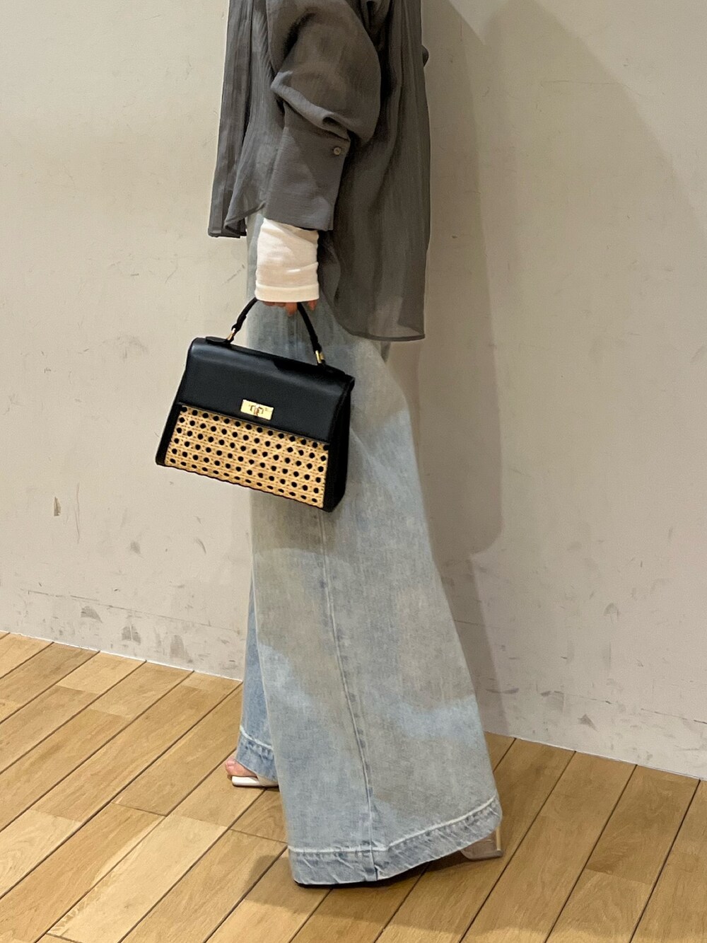 ホワイト系のサンダル、ブラック系のハンドバッグ、ブルー系のデニムパンツを着用したレディースの春コーディネートの4枚目の写真