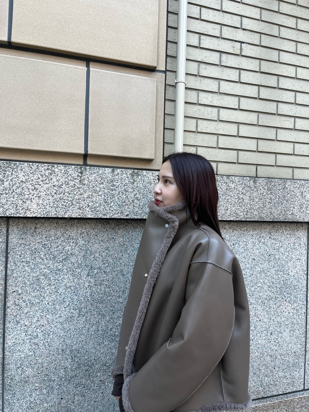 ベージュ系のムートンコート、ブラウン系のTシャツ/カットソー、ブラウン系のスカートを着用したレディースの冬コーディネートの6枚目の写真