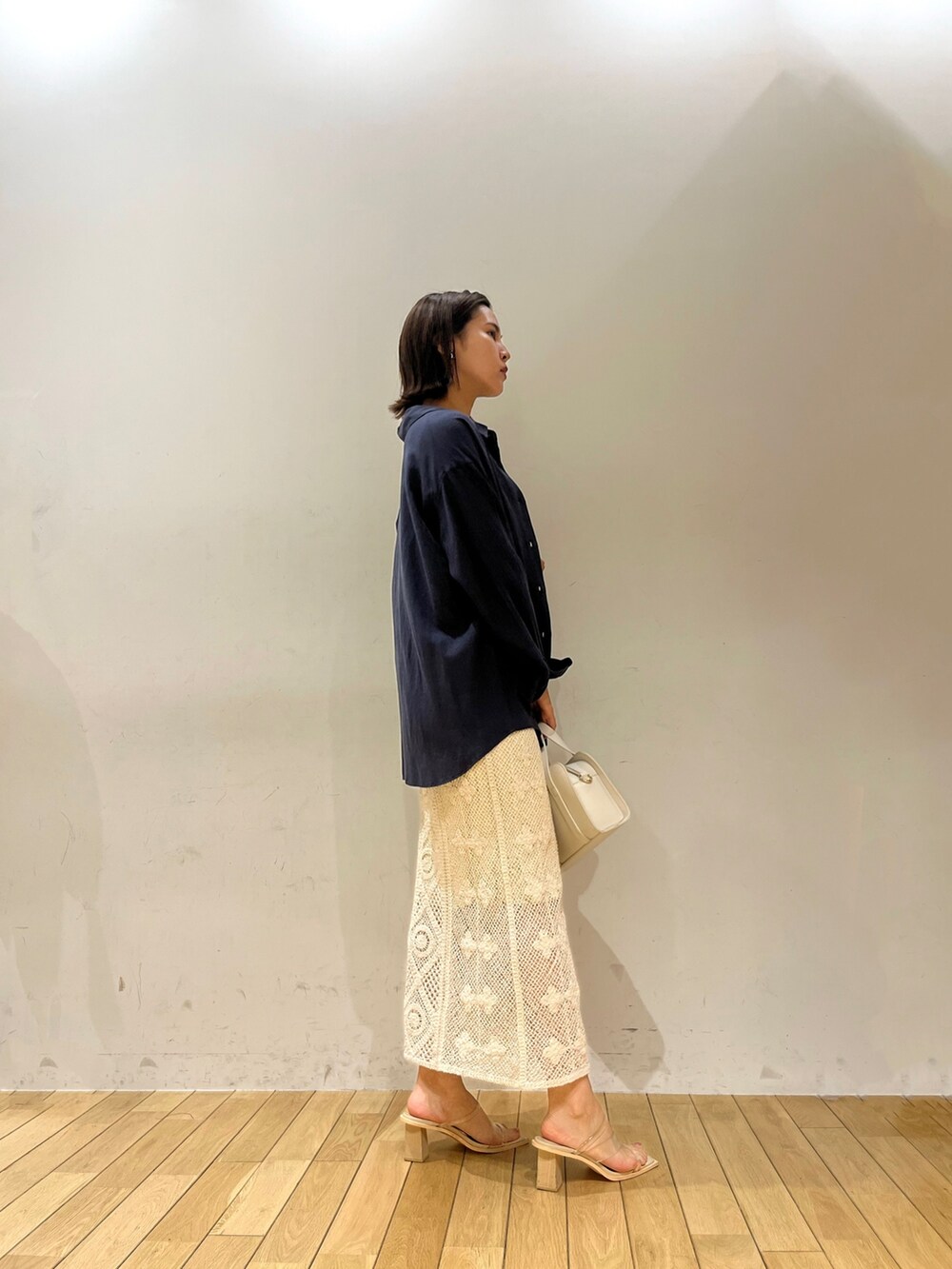 ホワイト系のニット/セーター、ホワイト系のショルダーバッグ、ブルー系のシャツ/ブラウスを着用したレディースの春コーディネートの2枚目の写真