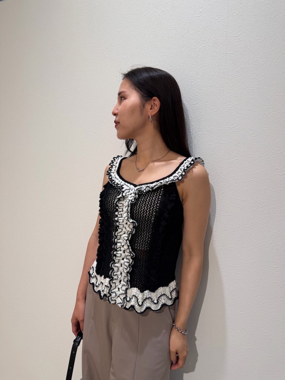 ベージュ系のその他パンツ、ブラック系のニット/セーター、ブラック系のハンドバッグを着用したレディースの夏コーディネートの4枚目の写真