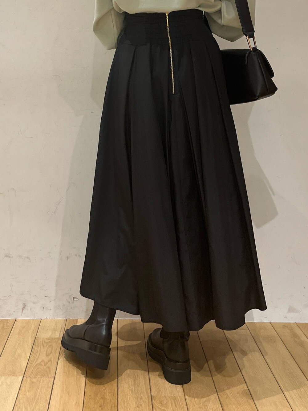 ブラック系のブーツ、ブラック系のスカート、グリーン系のニット/セーターを着用したレディースの冬コーディネートの7枚目の写真