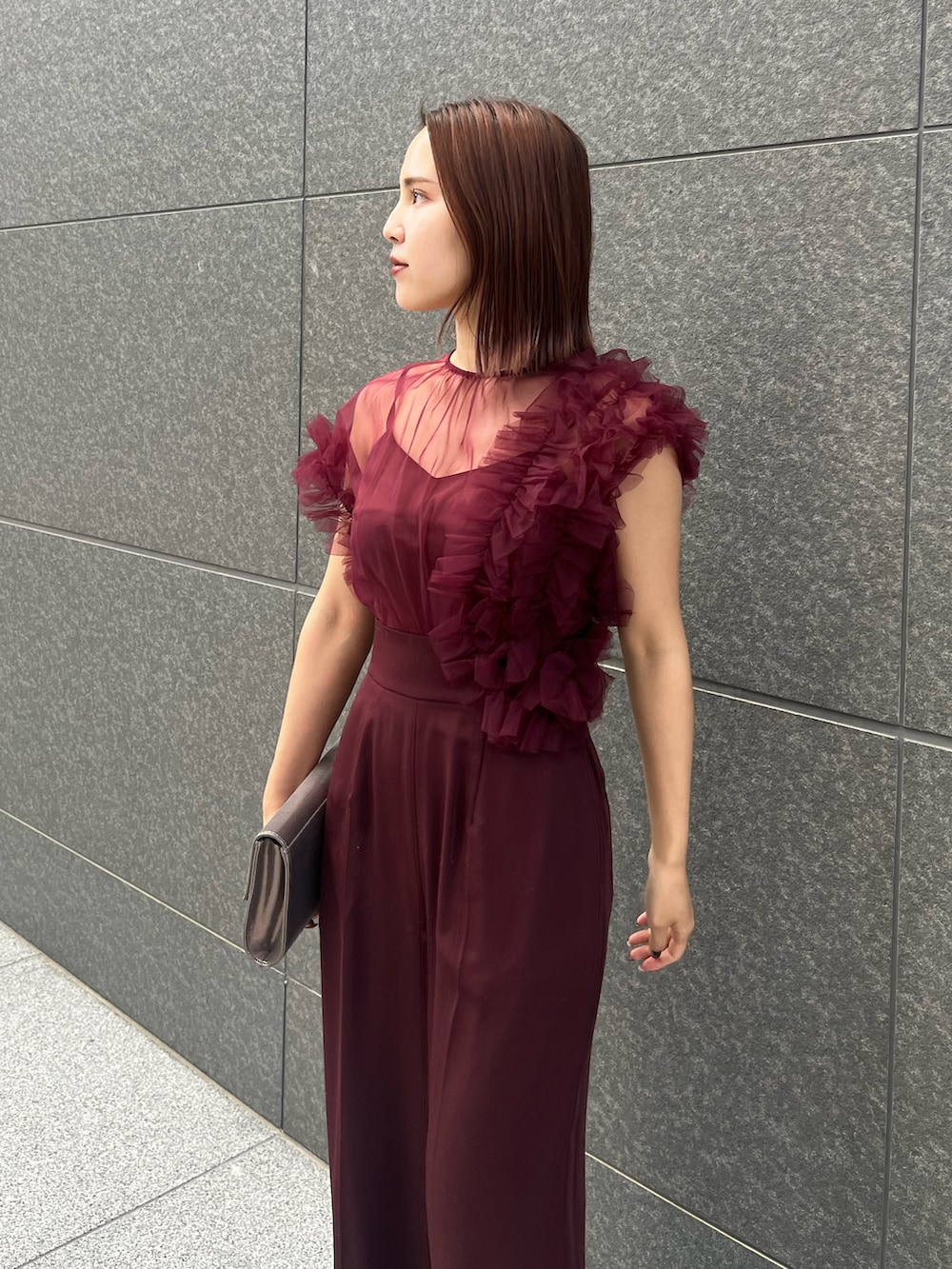 シルバー系のハンドバッグ、レッド系のパンツドレスを着用したレディースの冬コーディネートの4枚目の写真