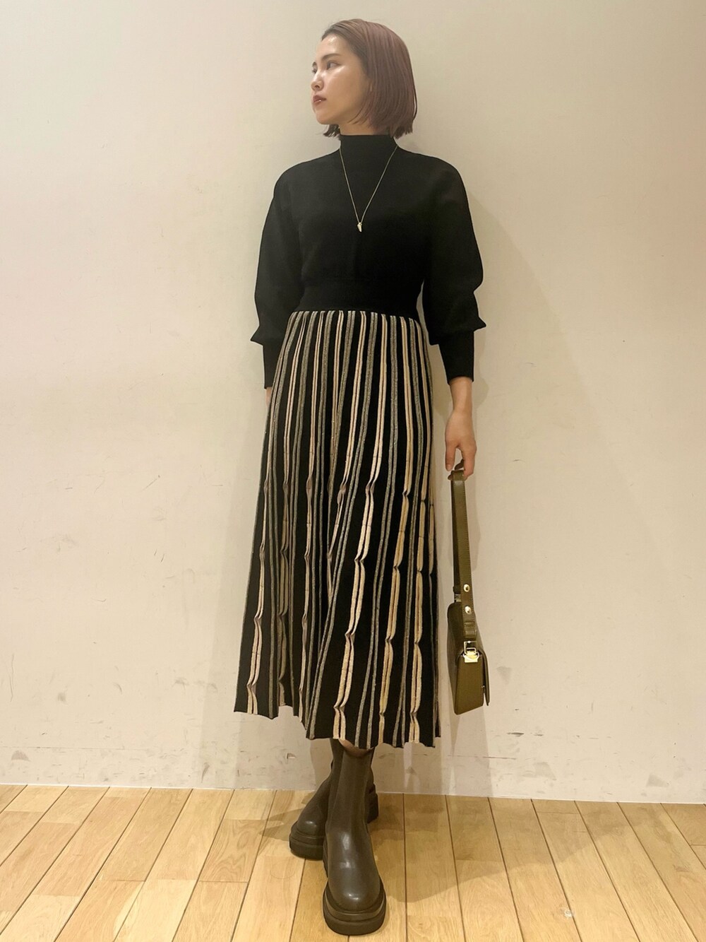 ブラック系のワンピース、ブラウン系のショルダーバッグ、ブラック系のダウンジャケット/コートを着用したレディースの秋コーディネートの2枚目の写真