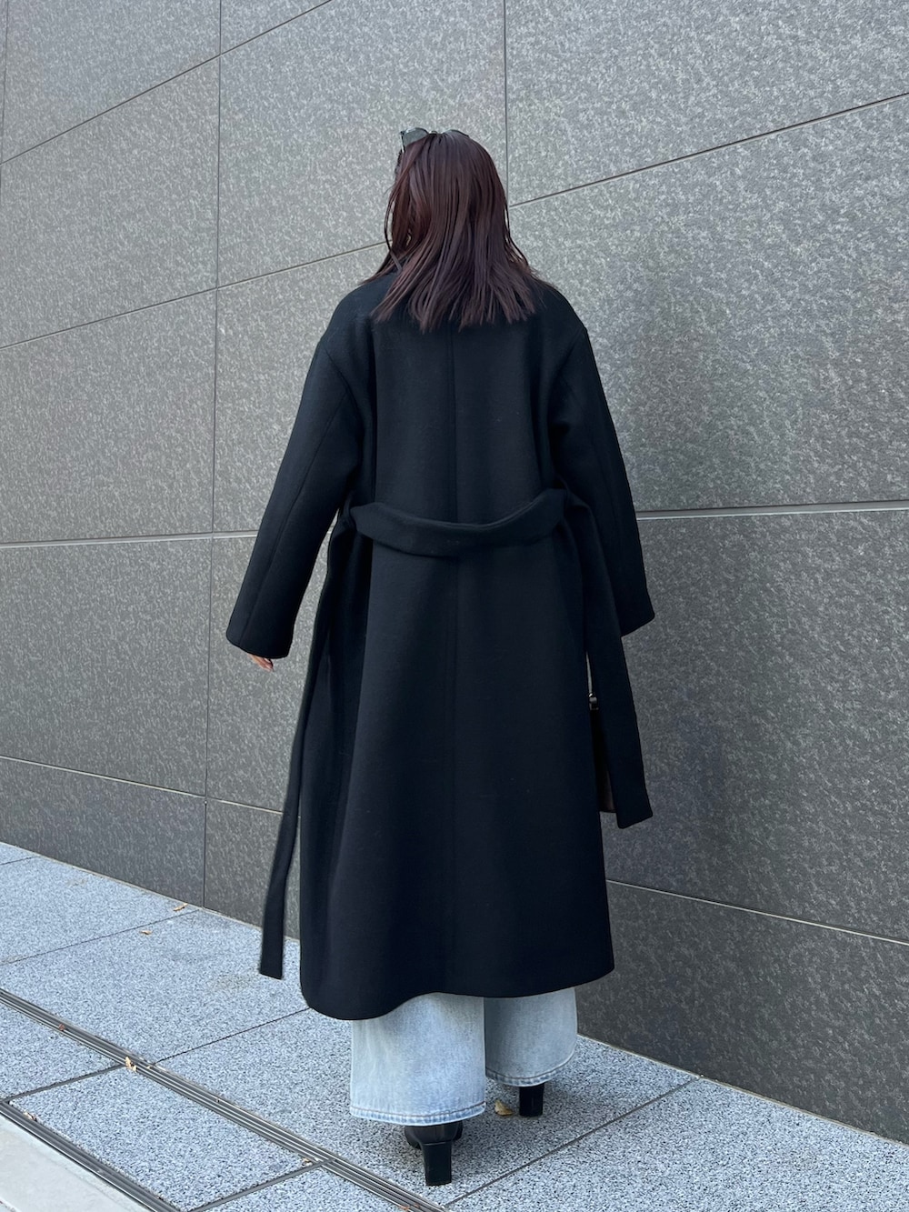 ブルー系のデニムパンツ、ブラウン系のハンドバッグ、ブラック系のブーツを着用したレディースの秋コーディネートの3枚目の写真