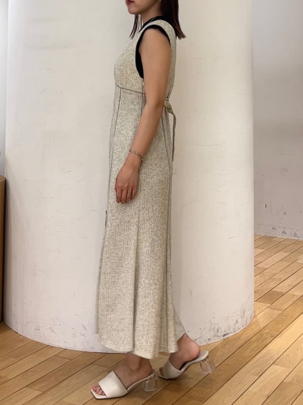 ブラック系のニット/セーター、ホワイト系のジャンパースカート、ブラック系のハンドバッグを着用したレディースの夏コーディネートの2枚目の写真