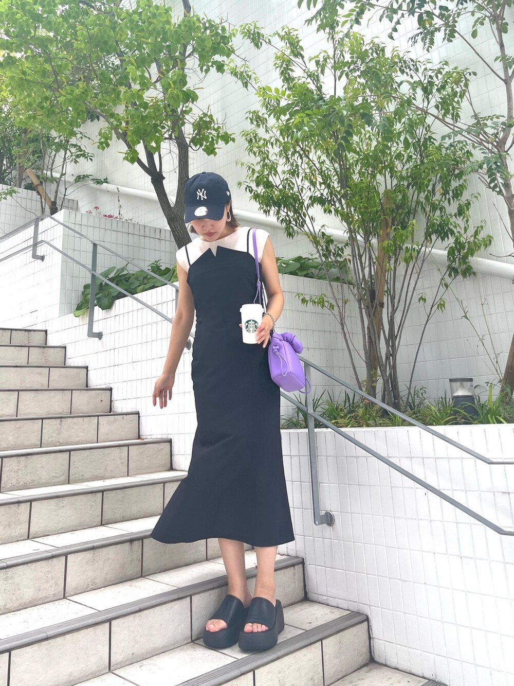 ブラック系のワンピース、ホワイト系のニット/セーター、パープル系のハンドバッグを着用したレディースの夏コーディネートの2枚目の写真