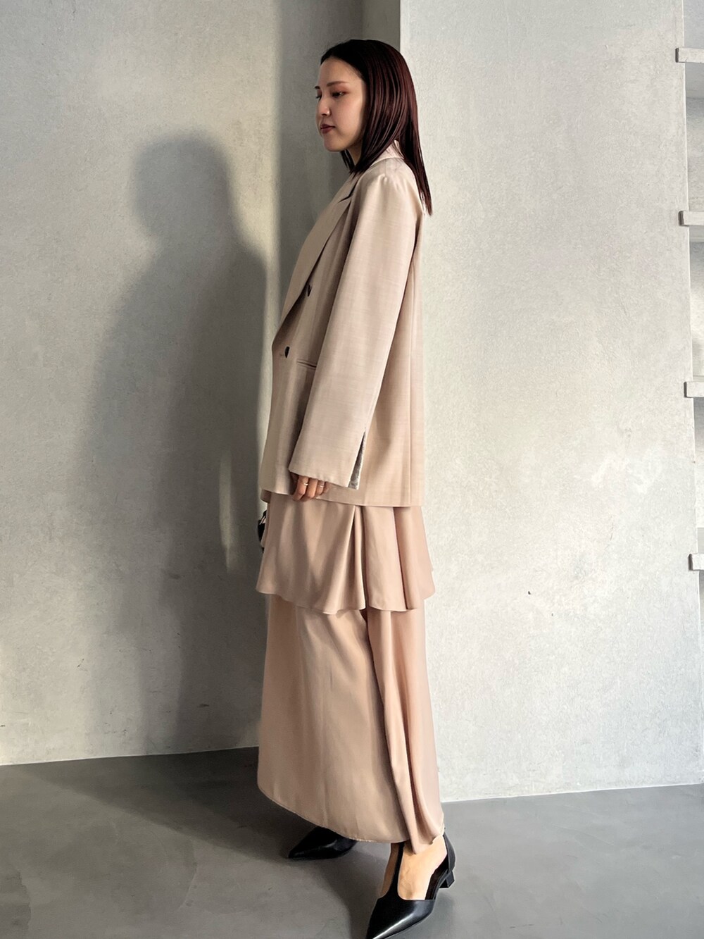 ベージュ系のテーラードジャケット、ベージュ系のワンピース、ブラウン系のハンドバッグを着用したレディースの冬コーディネートの2枚目の写真