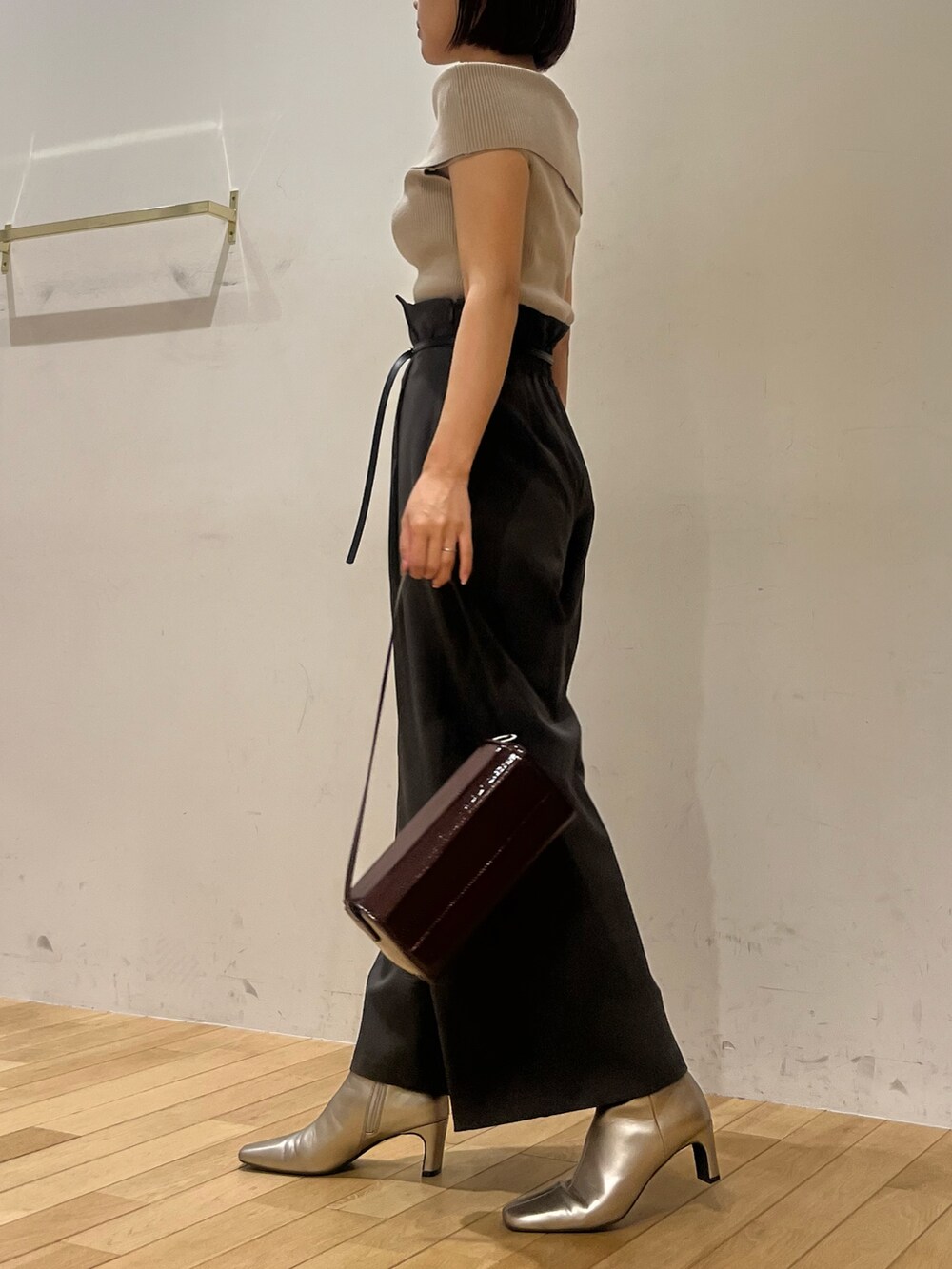 レッド系のショルダーバッグ、ベージュ系のニット/セーター、シルバー系のブーツを着用したレディースの秋コーディネートの2枚目の写真