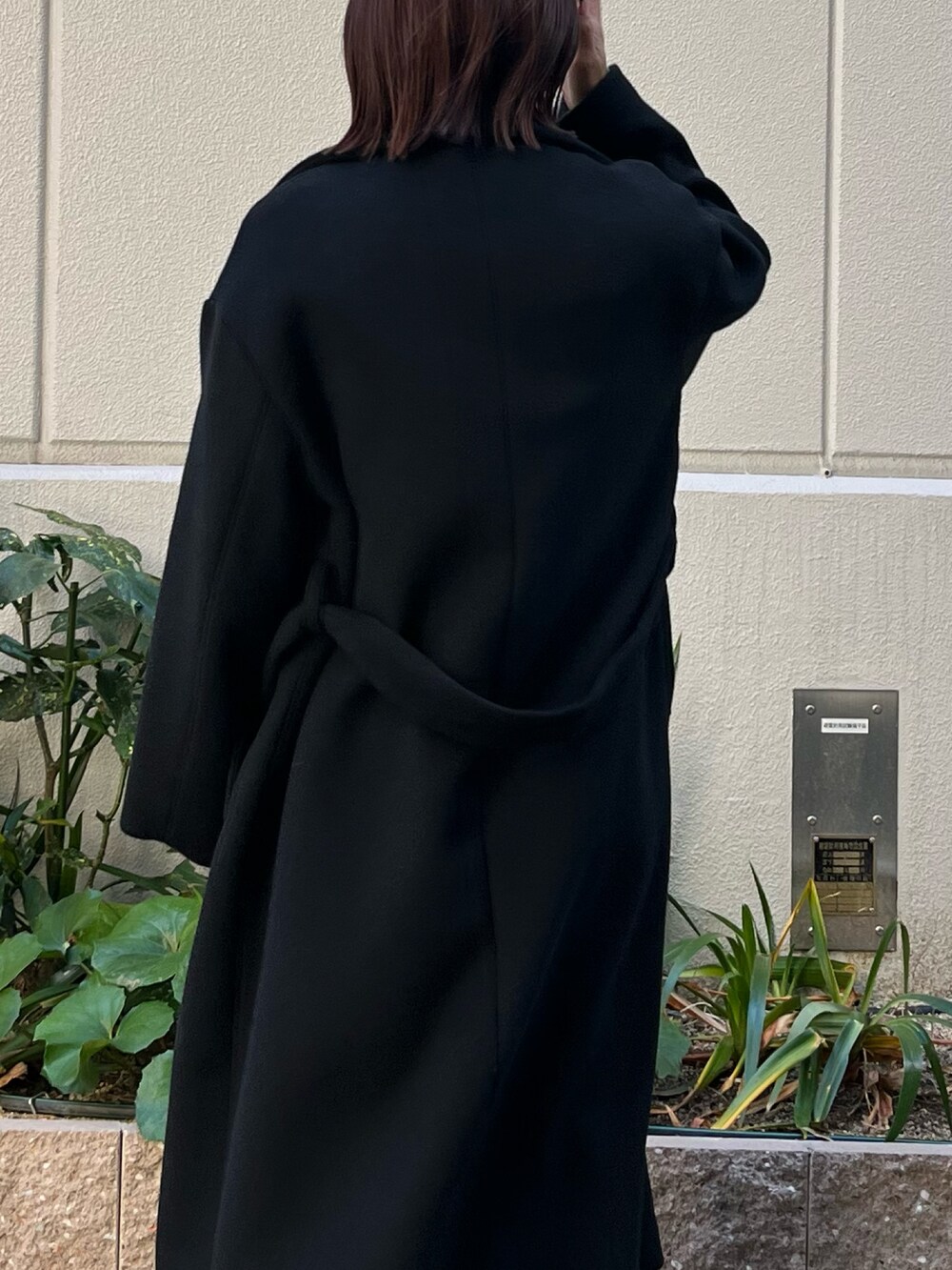 ブラック系のチェスターコート、グレー系のワンピースを着用したレディースの冬コーディネートの6枚目の写真