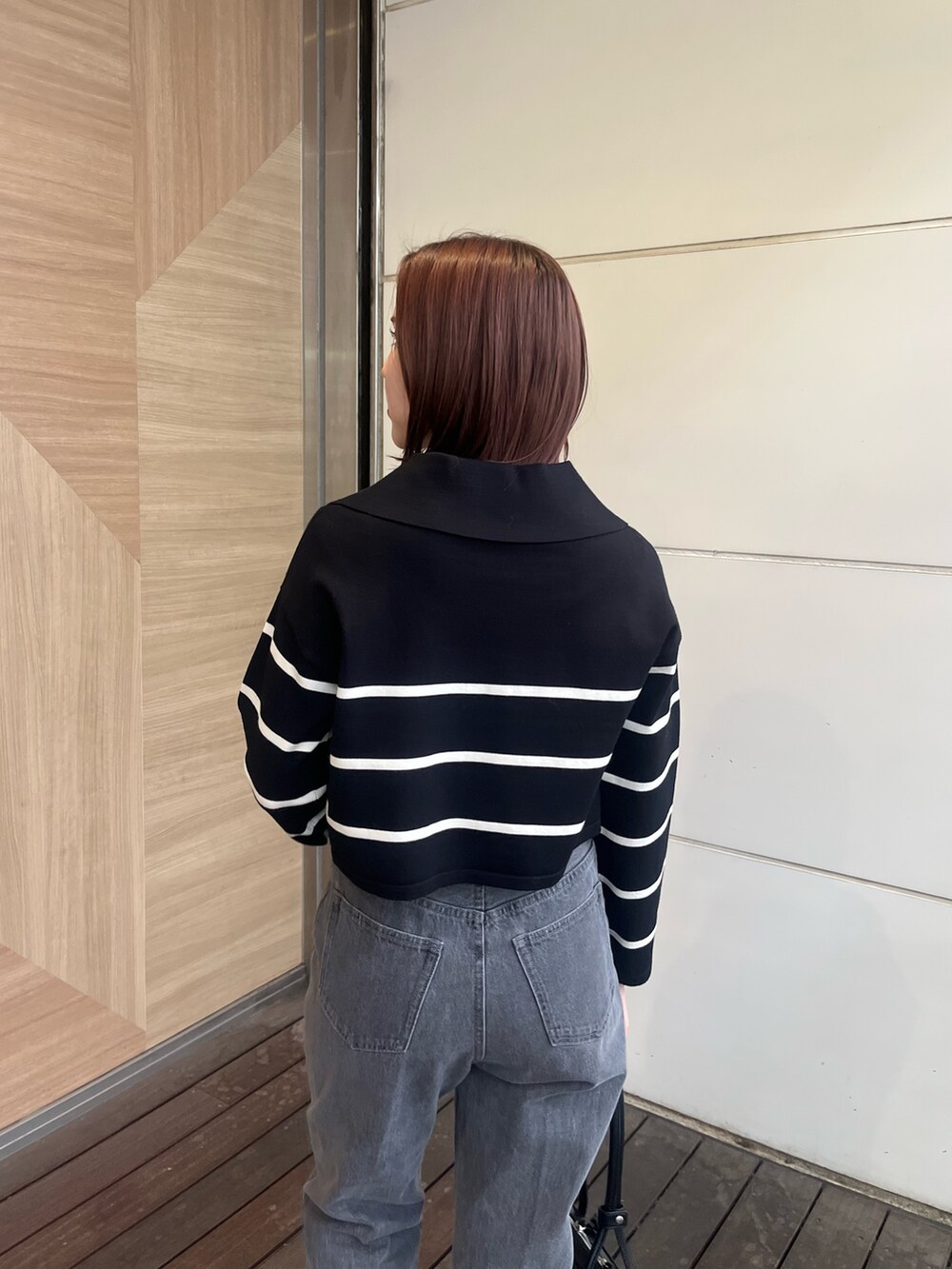 ブラック系のデニムパンツ、ブラック系のニット/セーター、ブラック系のショルダーバッグを着用したレディースの冬コーディネートの6枚目の写真