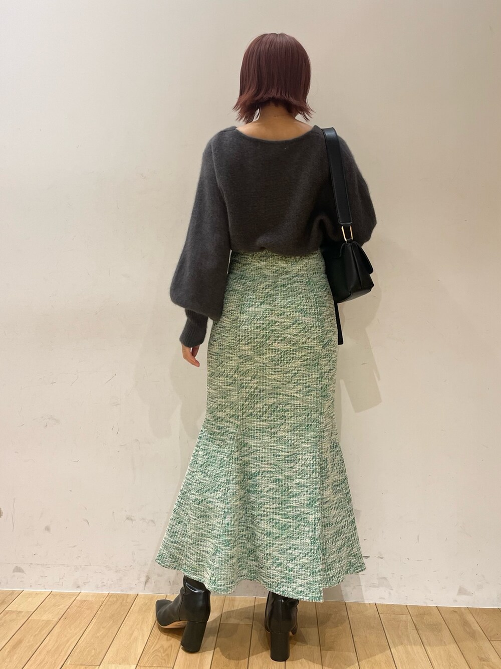 グレー系のニット/セーター、ブラック系のショルダーバッグ、ブラック系のブーツを着用したレディースの秋コーディネートの2枚目の写真