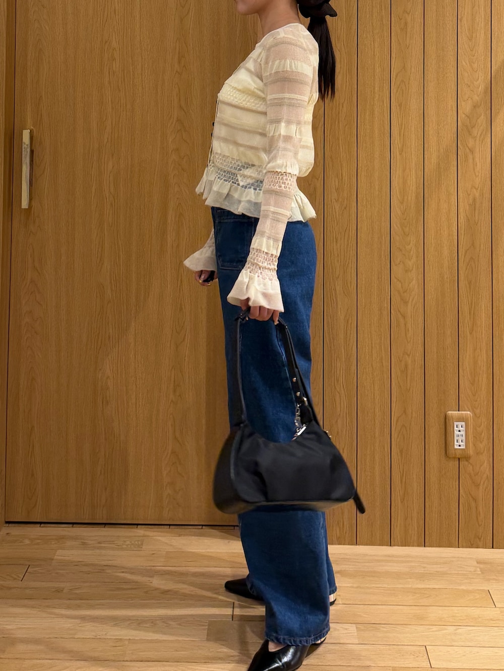 ブルー系のデニムパンツ、ブラック系のハンドバッグ、ホワイト系のニット/セーターを着用したレディースの春コーディネートの2枚目の写真