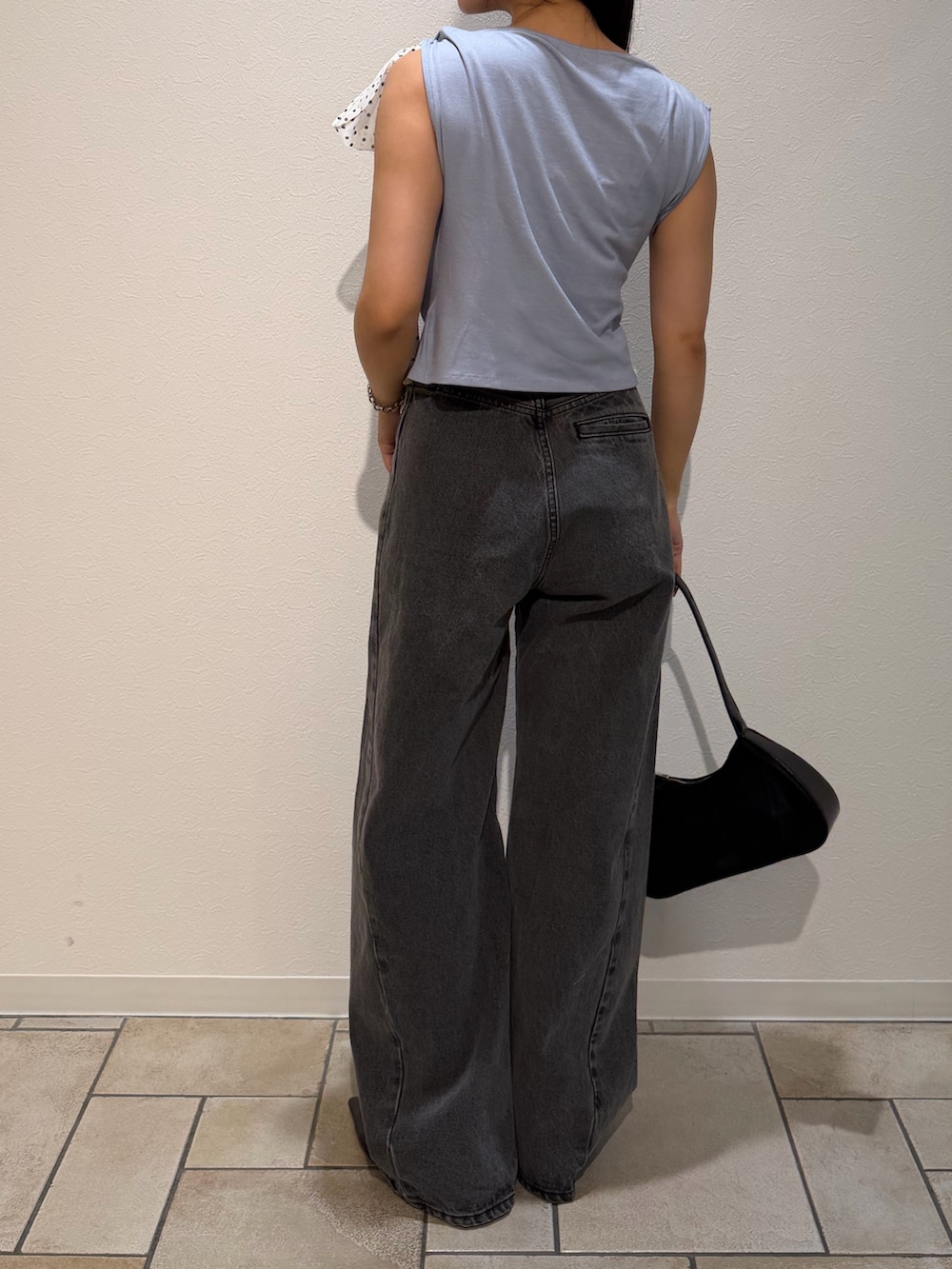 ブラック系のデニムパンツ、ブラック系のハンドバッグ、ブルー系のTシャツ/カットソーを着用したレディースの夏コーディネートの3枚目の写真