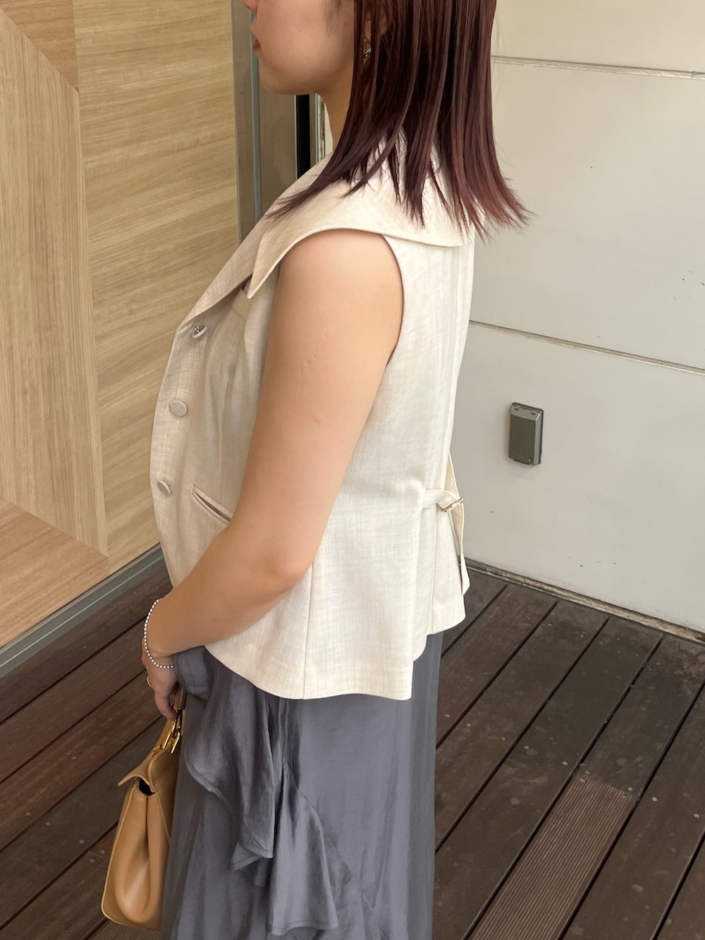 ホワイト系のベスト、グレー系のワンピース、ブラウン系のハンドバッグを着用したレディースの夏コーディネートの5枚目の写真