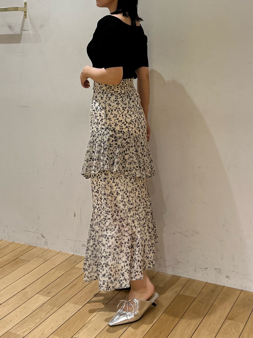 シルバー系のサンダル、ホワイト系のスカート、ブラック系のニット/セーターを着用したレディースの春コーディネートの2枚目の写真