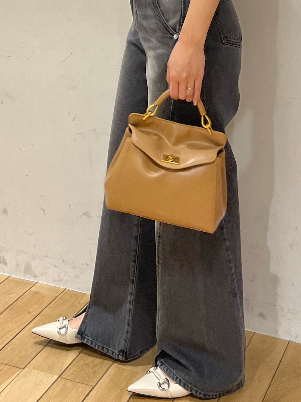 ブラック系のニット/セーター、ブラック系のデニムパンツ、ブラウン系のハンドバッグを着用したレディースの春コーディネートの7枚目の写真