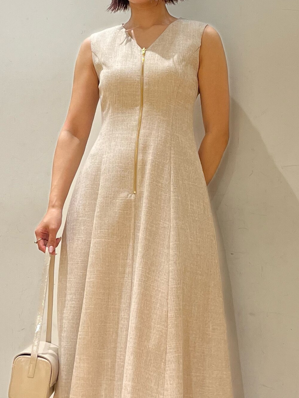 ホワイト系のショルダーバッグ、ベージュ系のワンピース、ブラック系のブーツを着用したレディースの夏コーディネートの5枚目の写真