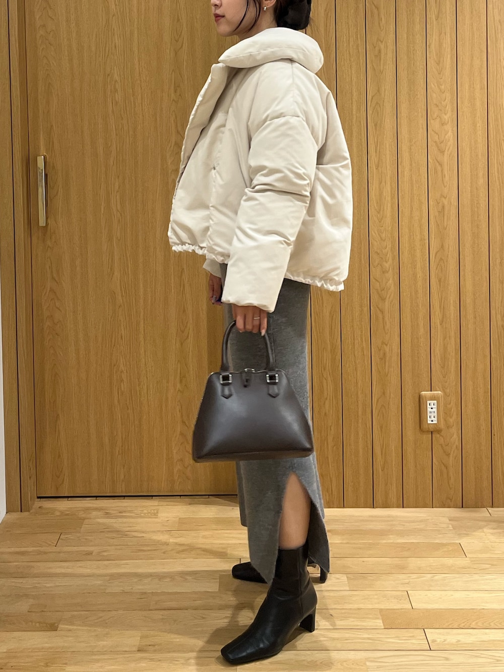 グレー系のワンピース、ホワイト系のダウンジャケット/コート、ブラウン系のボストンバッグを着用したレディースの秋コーディネートの2枚目の写真