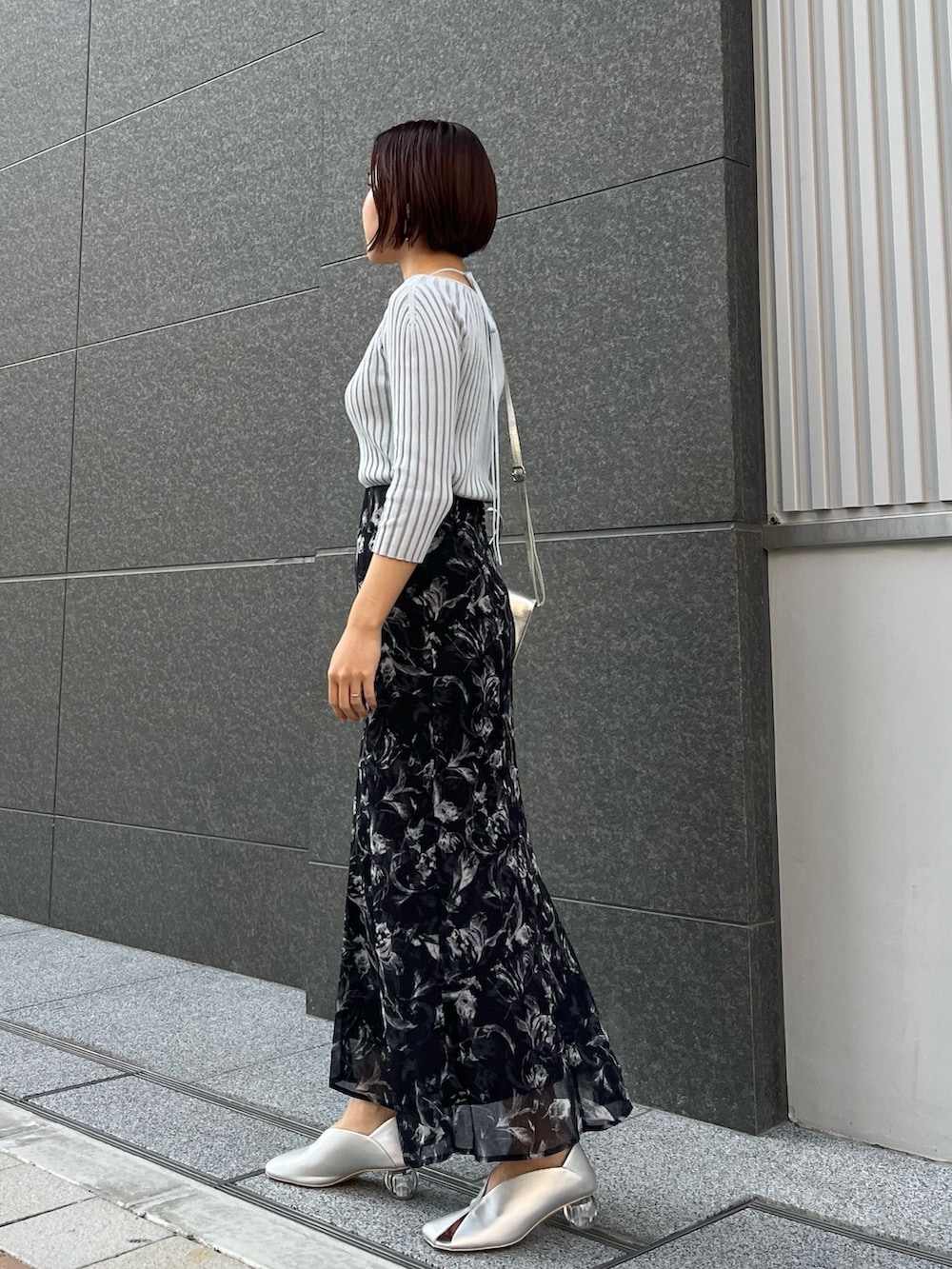 ブラック系のスカート、シルバー系のパンプス、ブルー系のニット/セーターを着用したレディースの春コーディネートの2枚目の写真