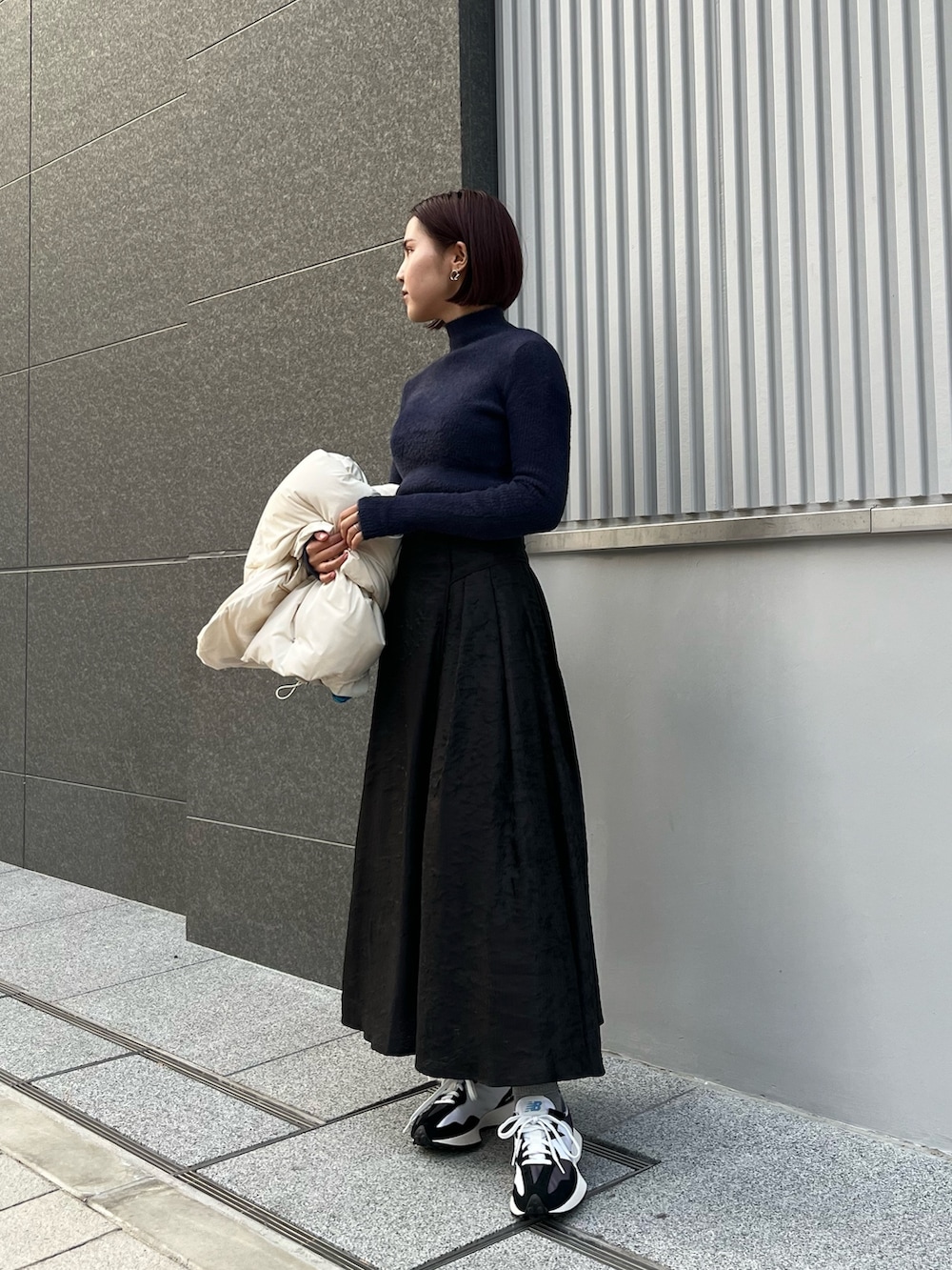 ホワイト系のダウンジャケット/コート、ブルー系のニット/セーター、ブラック系のスカートを着用したレディースの冬コーディネートの2枚目の写真