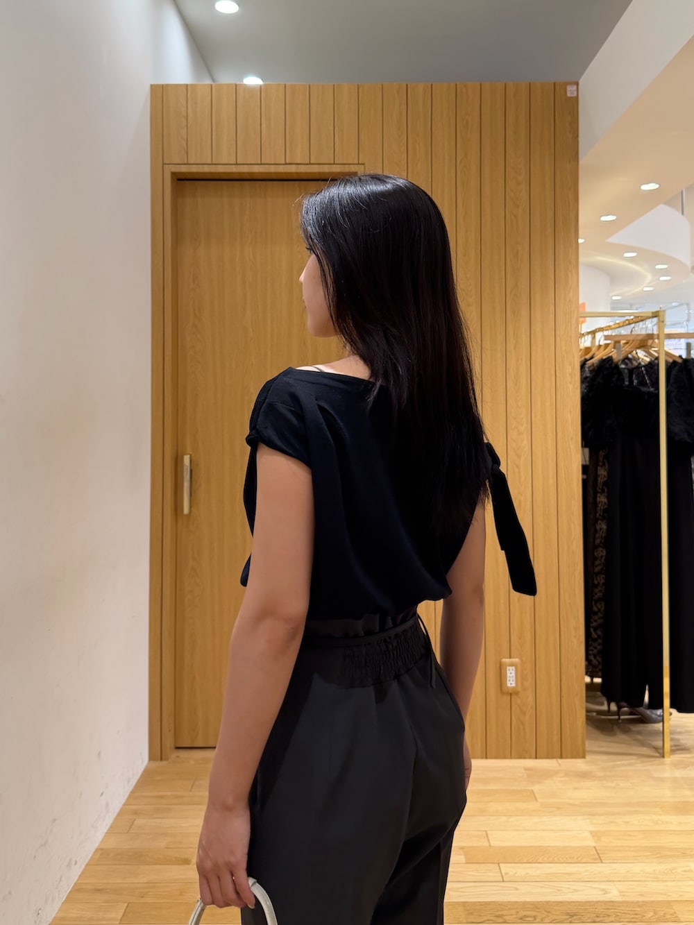 グレー系のその他パンツ、ブラック系のニット/セーター、ホワイト系のハンドバッグを着用したレディースの夏コーディネートの5枚目の写真