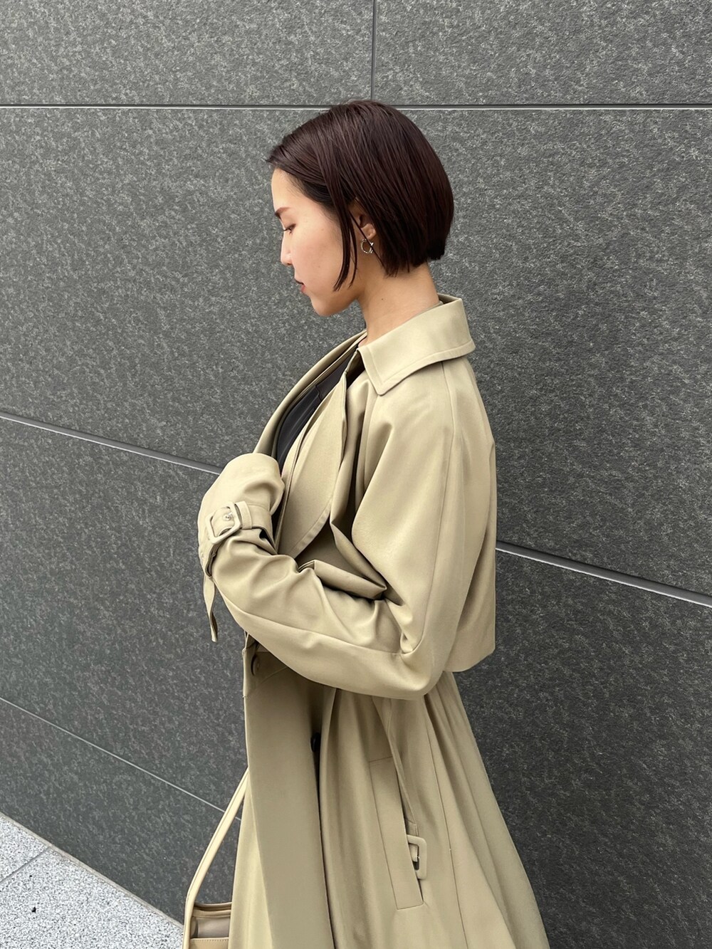 グリーン系のトレンチコート、シルバー系のパンプス、ブラック系のパンツドレスを着用したレディースの春コーディネートの5枚目の写真