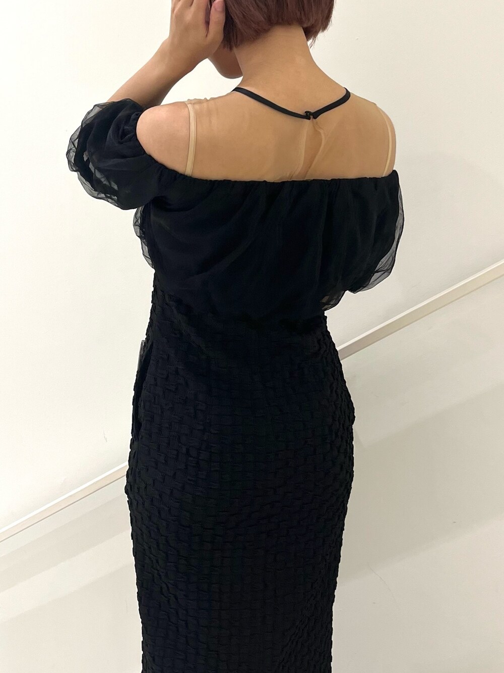 シルバー系のハンドバッグ、ブラック系のパンプス、ブラック系のドレスを着用したレディースの冬コーディネートの5枚目の写真