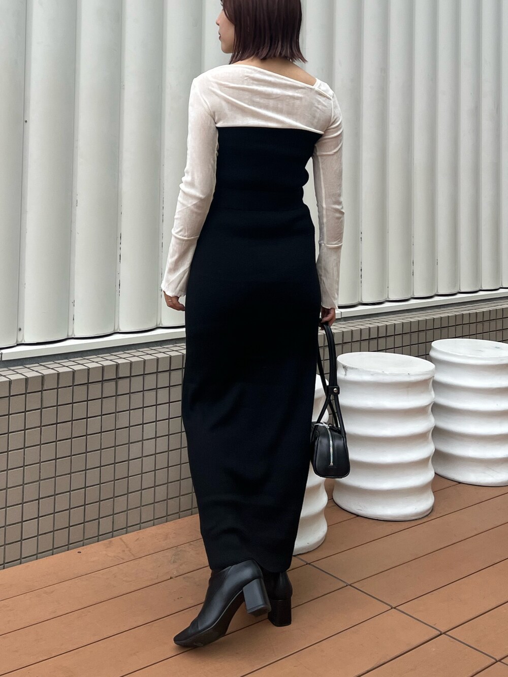 ブラック系のショルダーバッグ、ブラック系のワンピース、ホワイト系のTシャツ/カットソーを着用したレディースの秋コーディネートの4枚目の写真