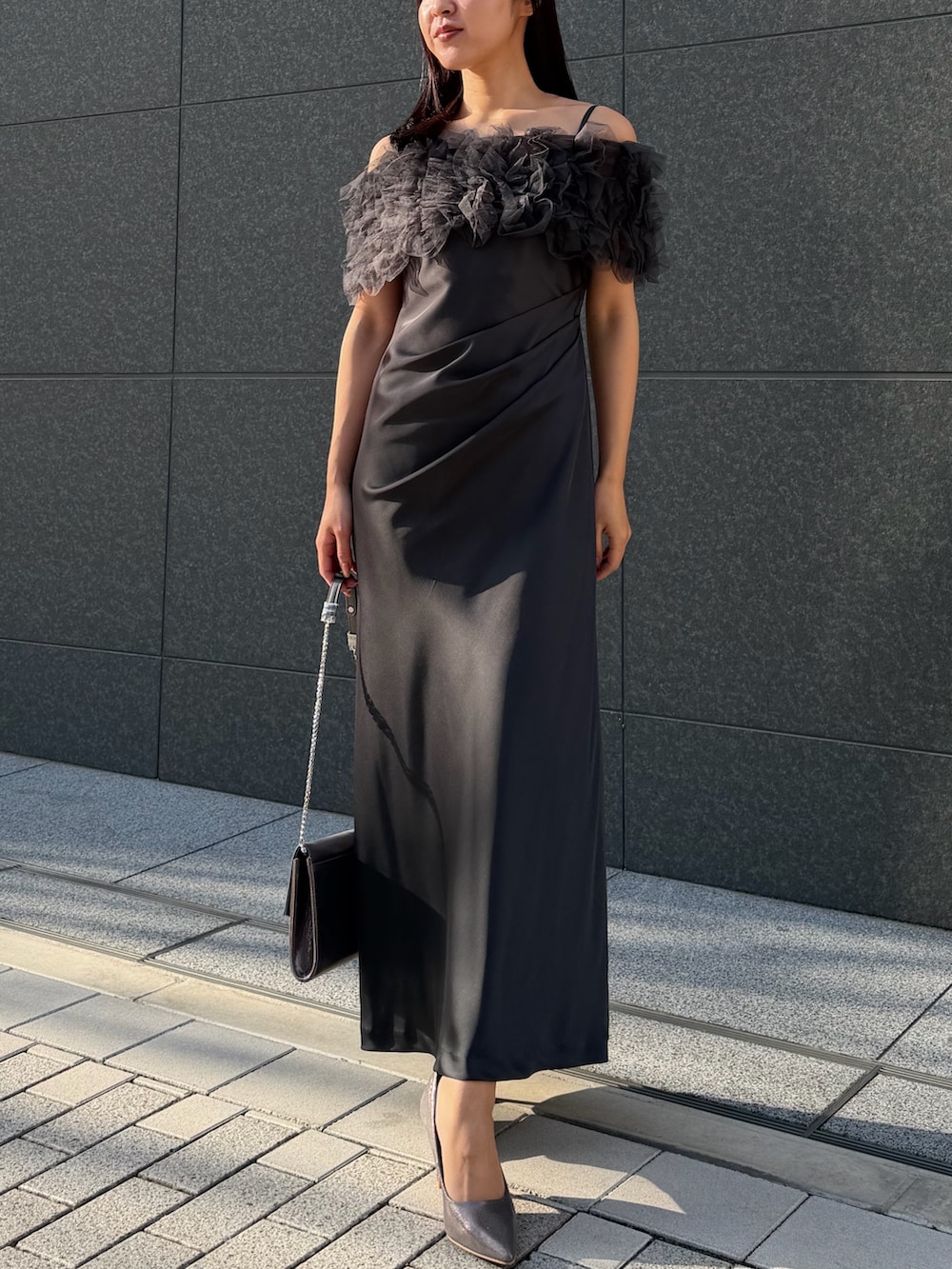 シルバー系のクラッチバッグ、シルバー系のパンプス、グレー系のドレスを着用したレディースの冬コーディネートの4枚目の写真