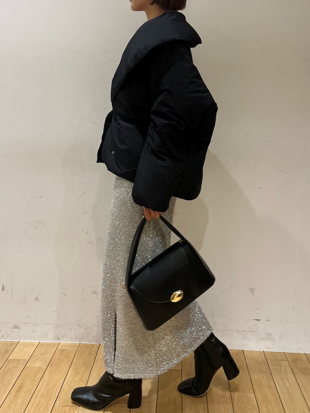 ブラック系のブーツ、ブラック系のハンドバッグ、シルバー系のスカートを着用したレディースの冬コーディネートの3枚目の写真