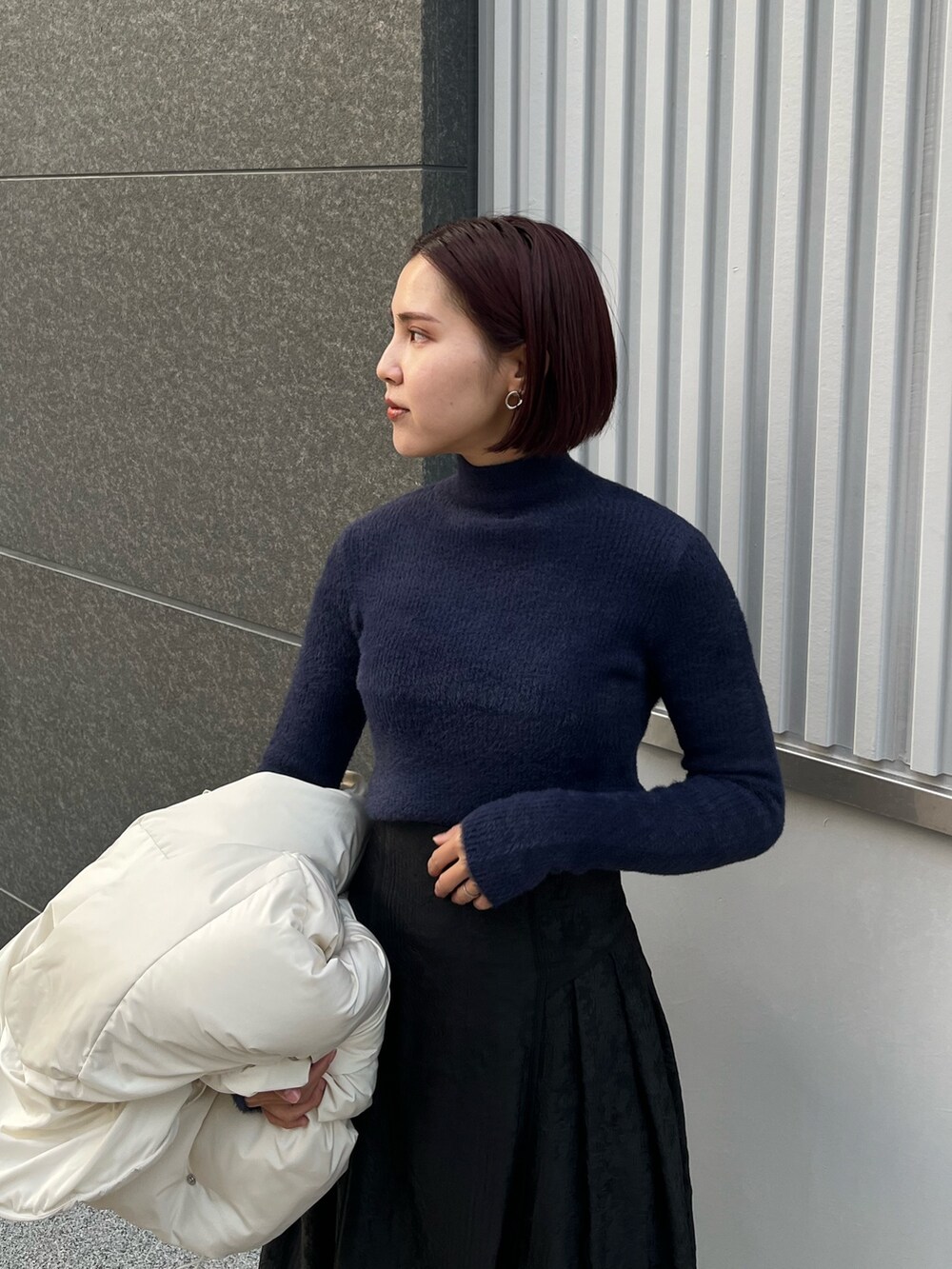 ホワイト系のダウンジャケット/コート、ブルー系のニット/セーター、ブラック系のスカートを着用したレディースの冬コーディネートの5枚目の写真