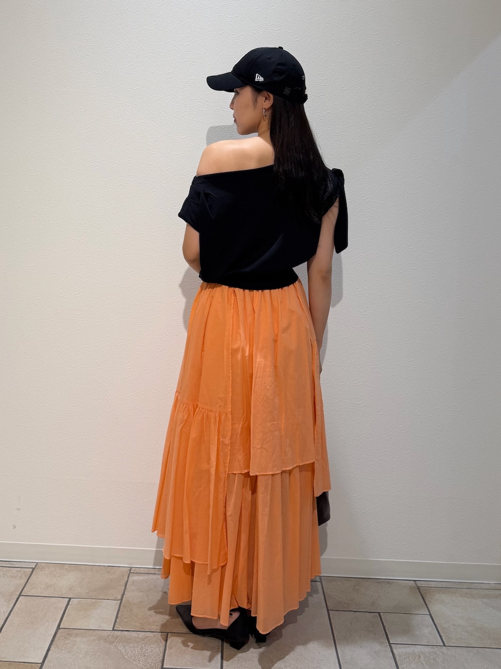 ブラック系のパンプス、ブラウン系のハンドバッグ、オレンジ系のスカートを着用したレディースの夏コーディネートの3枚目の写真