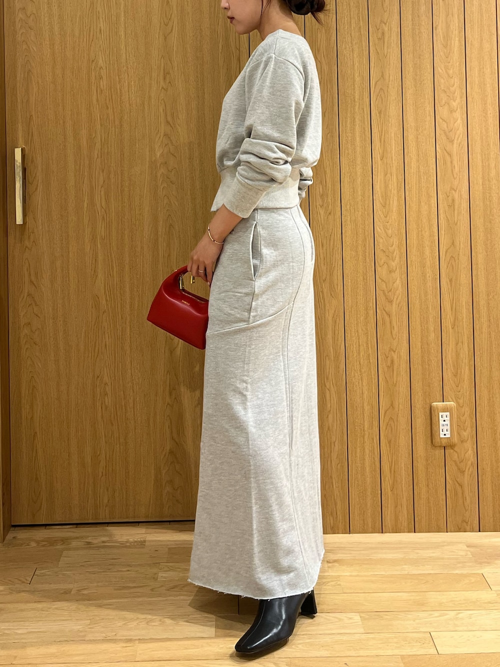 グレー系のスウェット、グレー系のスカート、レッド系のハンドバッグを着用したレディースの秋コーディネートの3枚目の写真