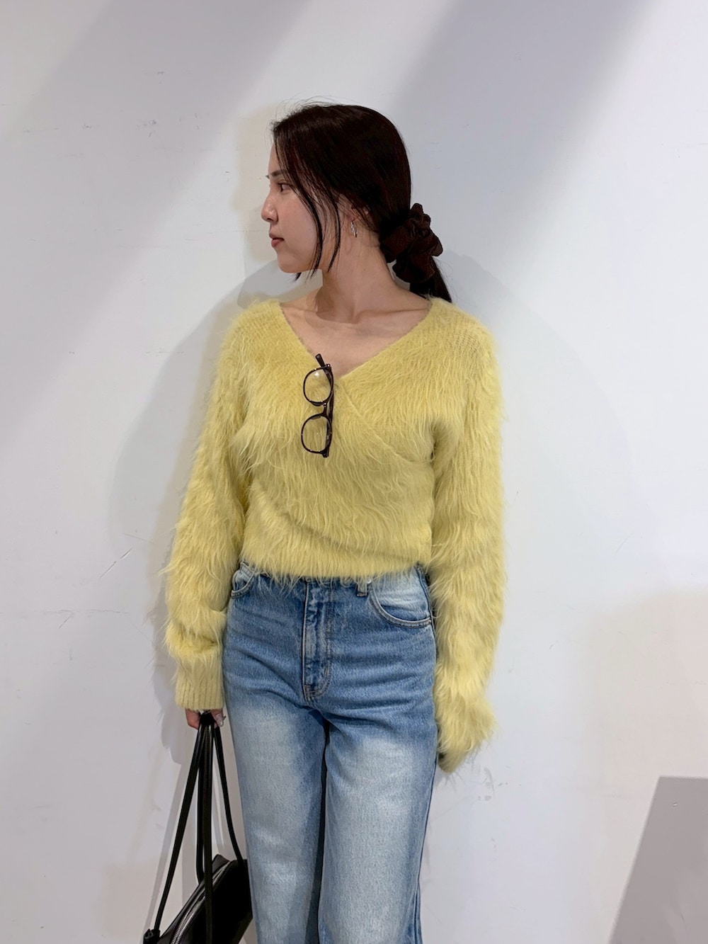 ブルー系のデニムパンツ、ブラック系のブーツ、イエロー系のニット/セーターを着用したレディースの秋コーディネートの4枚目の写真