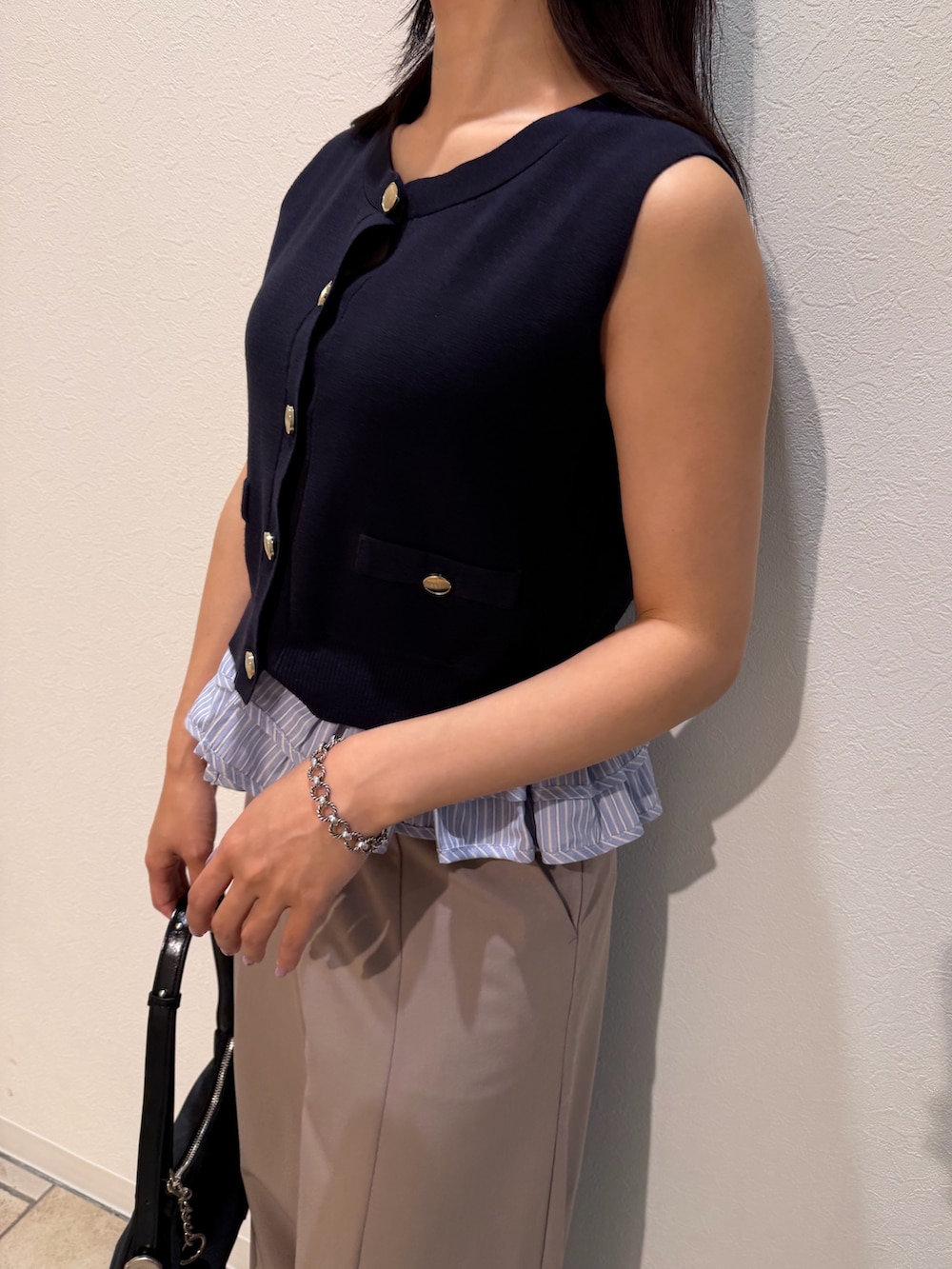 ベージュ系のその他パンツ、ブルー系のニット/セーター、ブラック系のハンドバッグを着用したレディースの夏コーディネートの6枚目の写真