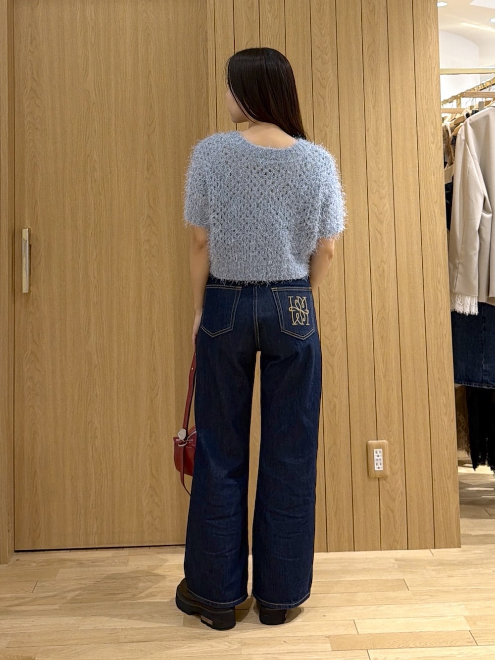ブルー系のデニムパンツ、レッド系のハンドバッグ、ブルー系のニット/セーターを着用したレディースの秋コーディネートの3枚目の写真