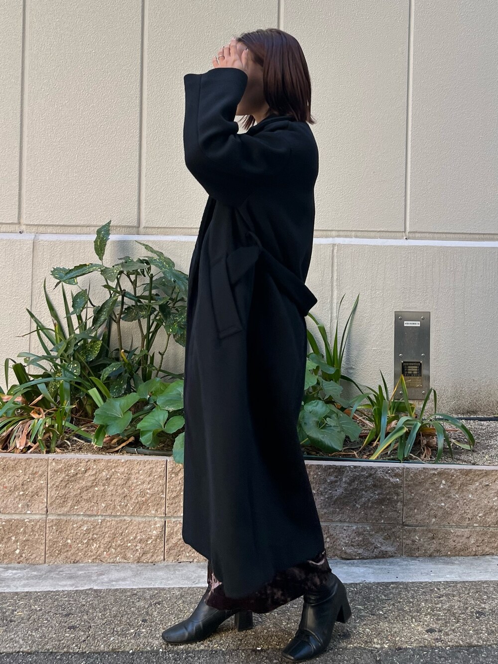 ブラック系のチェスターコート、グレー系のワンピースを着用したレディースの冬コーディネートの2枚目の写真