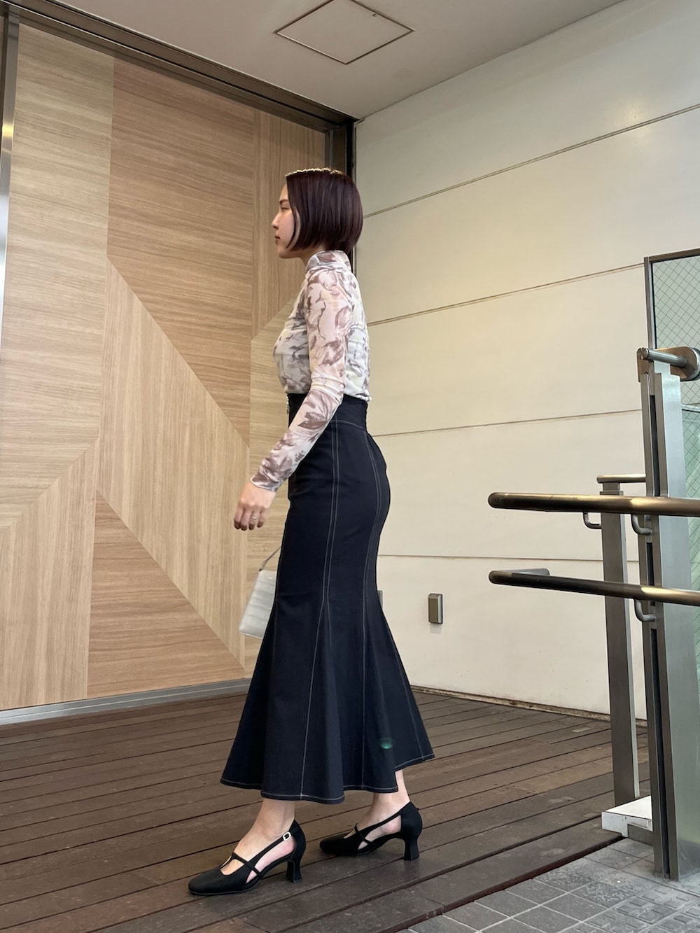 ブラック系のスカート、ブラック系のパンプス、イエロー系のTシャツ/カットソーを着用したレディースの春コーディネートの2枚目の写真