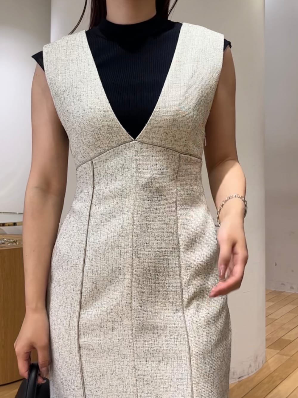 ブラック系のニット/セーター、ホワイト系のジャンパースカート、ブラック系のハンドバッグを着用したレディースの夏コーディネートの5枚目の写真