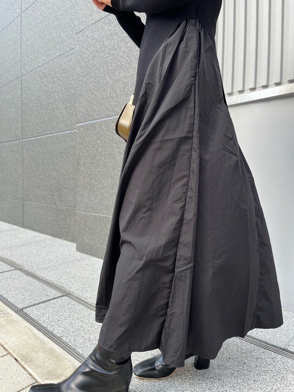 ブラック系のワンピース、ブラック系のブーツ、ブラウン系のショルダーバッグを着用したレディースの冬コーディネートの7枚目の写真
