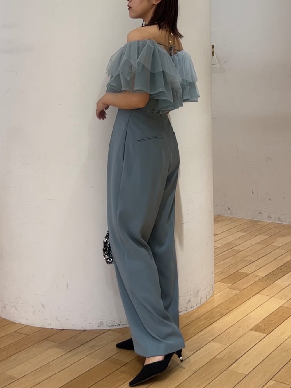 シルバー系のショルダーバッグ、ブラック系のパンプス、ブルー系のパンツドレスを着用したレディースの春コーディネートの2枚目の写真