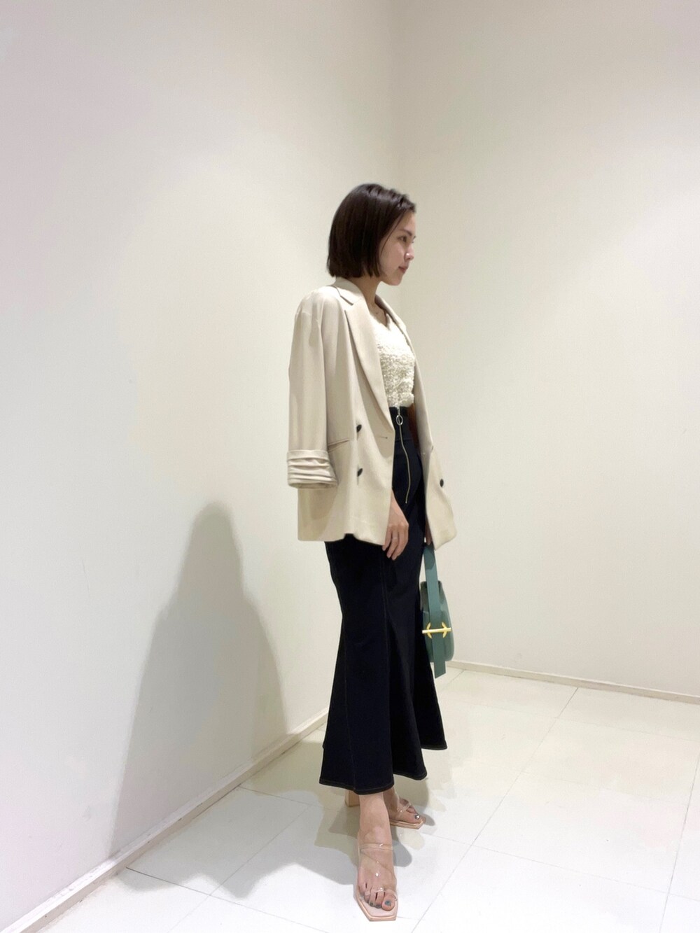 ベージュ系のテーラードジャケット、ホワイト系のニット/セーター、ブラック系のスカートを着用したレディースの春コーディネートの2枚目の写真