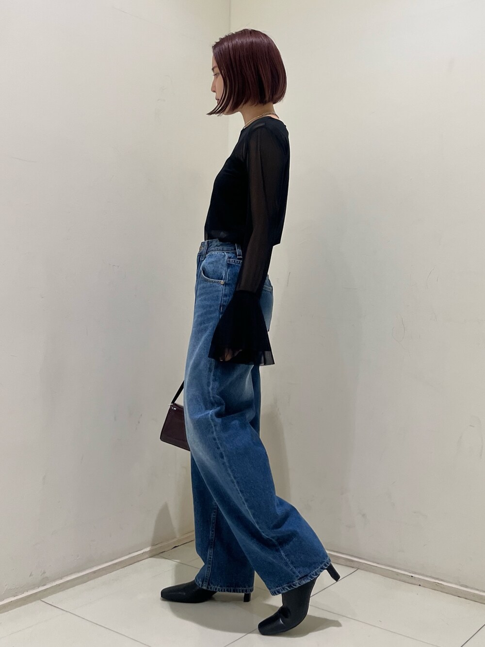 ブルー系のデニムパンツ、レッド系のショルダーバッグ、ブラック系のブーツを着用したレディースの秋コーディネートの3枚目の写真